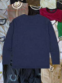 Lyle & Scott Langarmshirt in Marineblau aus reiner Baumwolle mit Rundhalsausschnitt, flach auf einem Kleiderhaufen