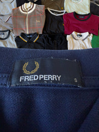Fred Perry Etikett in Marineblau mit goldenem Lorbeerkranz-Logo und Größenangabe S auf einem Baumwoll-Poloshirt