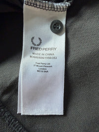 Just Casual Fred Perry Poloshirt Pflegeetikett mit Lorbeerkranz-Logo und Herstellerinformationen auf grauem Piqué-Stoff